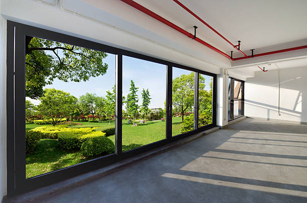 An empty room has a large glass window, where you can see the beautiful garden.